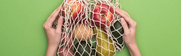 Top view of woman holding vegetables and fruits in string bag isolated on green — Stock Photo