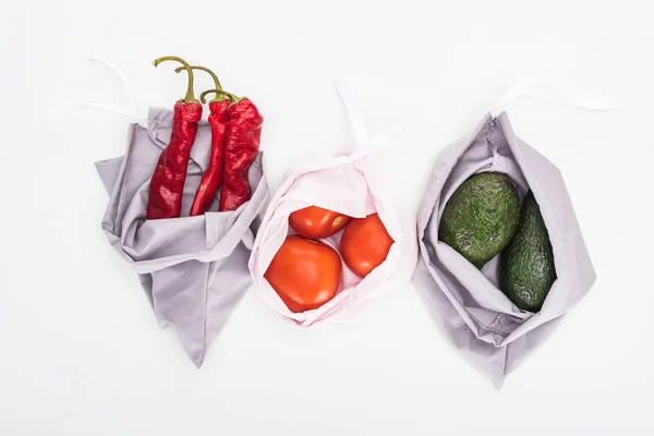 Vue de dessus des avocats, tomates et piments dans des sacs écologiques isolés sur blanc — Photo de stock