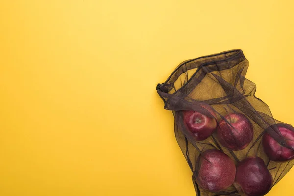 Vue du dessus des pommes dans un sac écologique en maille noire isolé sur jaune — Photo de stock