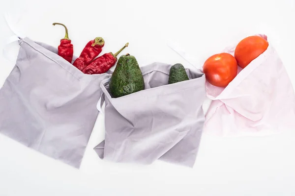 Top view of fresh avocados, tomatoes and chili peppers in eco friendly bags isolated on white — Stock Photo