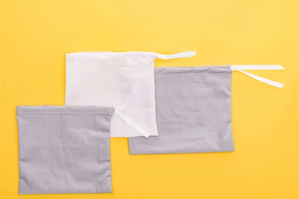 Top view of cotton white and grey eco friendly bags isolated on yellow — Stock Photo