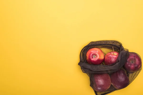 Top view of ripe apples in black eco friendly bag isolated on yellow — Stock Photo