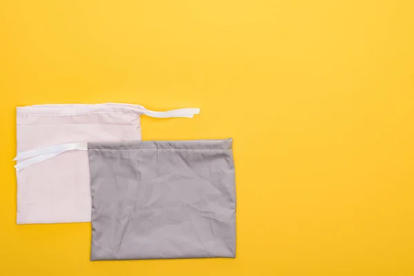 Вид на серый и белый экологически чистые сумки изолированы на желтый — стоковое фото