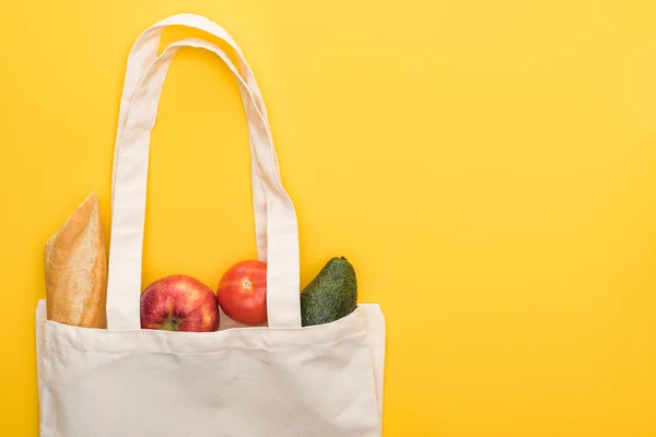 Vue de dessus des pommes mûres, baguette et avocat dans des sacs écologiques isolés sur jaune — Photo de stock