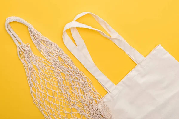 Top view of white cotton and string bags isolated on yellow — Stock Photo