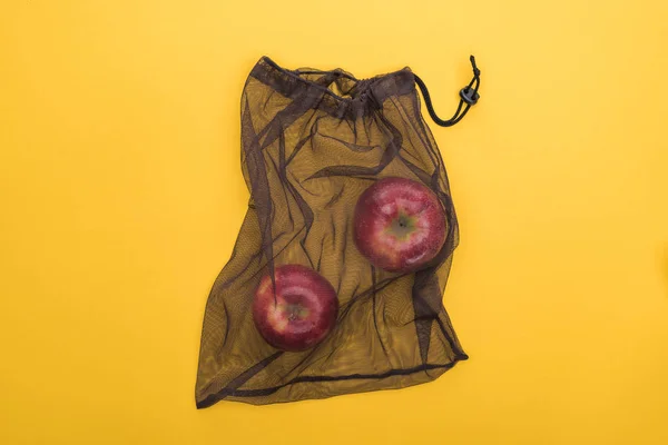 Top view of red apples in eco friendly black bag isolated on yellow — Stock Photo