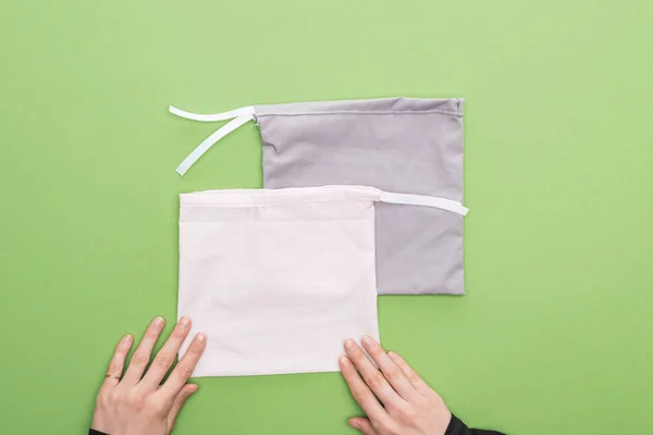 Vista recortada manos de la mujer y bolsas ecológicas aislados en verde - foto de stock