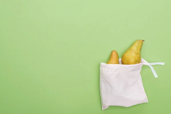 Vista superior de peras en bolsa blanca ecológica aislada en verde - foto de stock