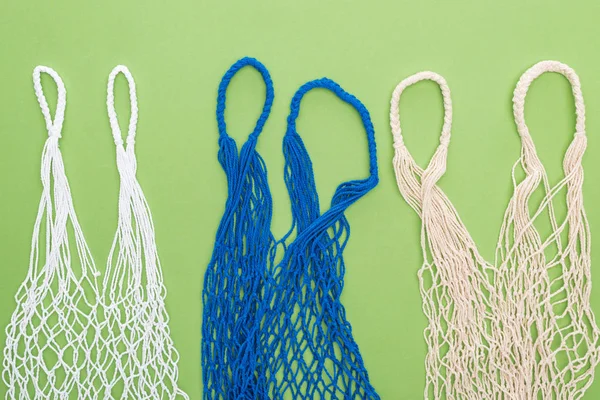 Top view of empty multicolored string bags isolated on green — Stock Photo