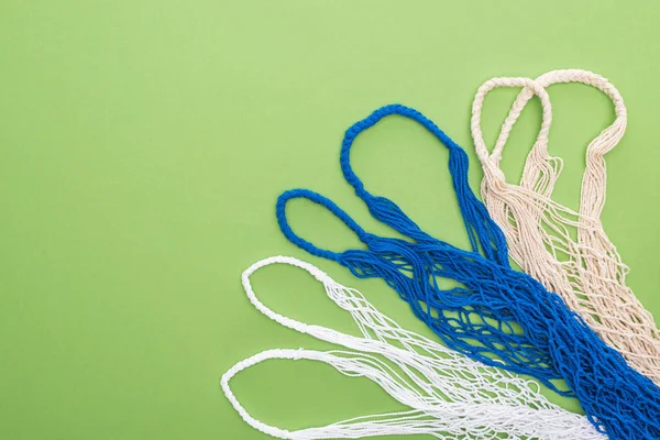 Top view of empty multicolored string bags isolated on green — Stock Photo