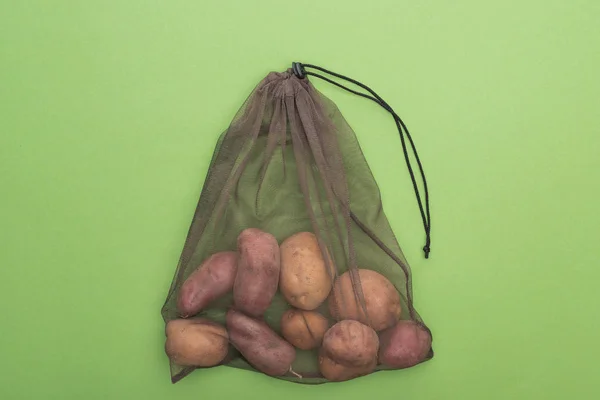 Вид зверху на свіжу цілу картоплю в екологічно чистій сумці ізольовано на зеленому — стокове фото