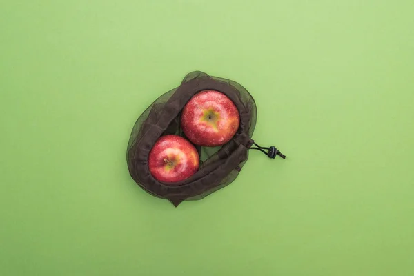 Top view of red ripe apples in eco friendly bag isolated on green — Stock Photo