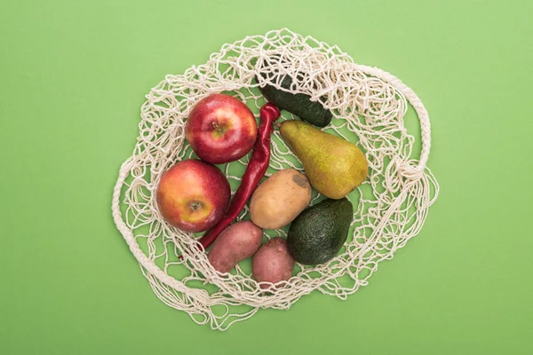 Blick von oben auf Gemüse und Obst in Schnur Tasche isoliert auf grün — Stockfoto