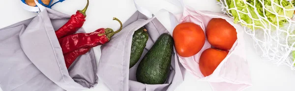 Vista dall'alto di avocado fresco, pomodori e peperoncino in sacchetti ecologici isolati su bianco, colpo panoramico — Foto stock