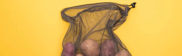 Top view of potatoes in eco friendly black mesh bag isolated on yellow, panoramic shot — Stock Photo