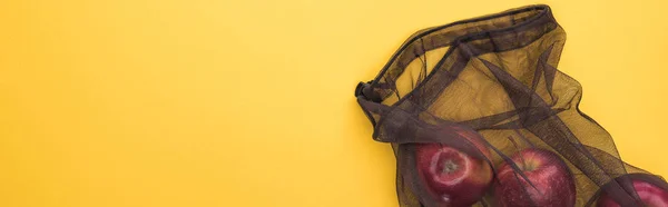 Top view of apples in eco friendly black mesh bag isolated on yellow, panoramic shot — Stock Photo