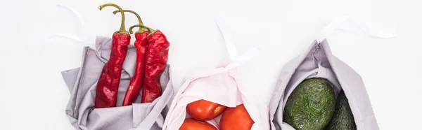 Blick von oben auf frische Avocados, Tomaten und Chilischoten in umweltfreundlichen Tüten isoliert auf weißen, panoramischen Aufnahmen — Stockfoto