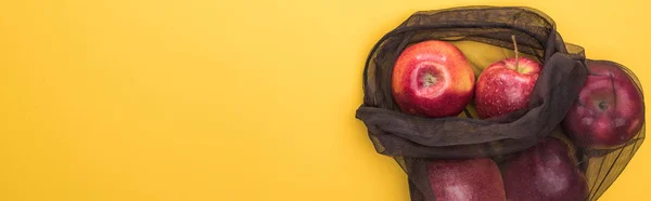 Vue de dessus des pommes dans un sac écologique en maille noire isolé sur jaune, panoramique — Photo de stock