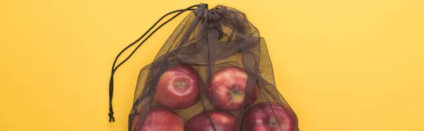 Vista superior de manzanas rojas en bolsa de malla negra ecológica aislada en amarillo, plano panorámico - foto de stock