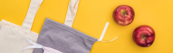 Top view of ripe apples near eco friendly bags isolated on yellow, panoramic shot — Stock Photo