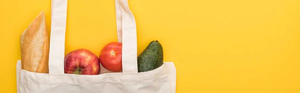 Vue de dessus des pommes mûres, baguette et avocat dans des sacs écologiques isolés sur jaune, panoramique — Photo de stock