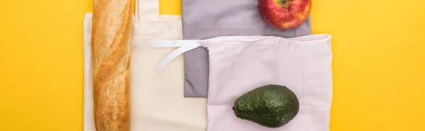 Vista dall'alto di mela, baguette e avocado su borse eco friendly isolate su giallo, colpo panoramico — Foto stock
