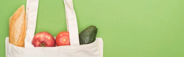 Vista superior de tomate, aguacate, manzana y baguette en bolsa ecológica aislado en verde, plano panorámico - foto de stock