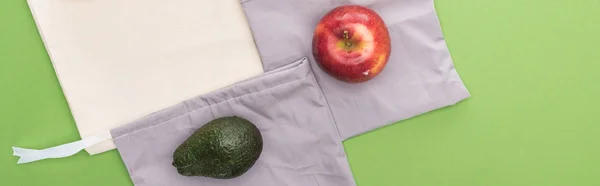 Vue de dessus de pomme et avocat sur sacs écologiques isolés sur vert, panoramique — Photo de stock