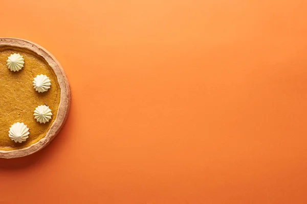 Vista superior de delicioso pastel de calabaza con crema batida en la superficie naranja con espacio de copia - foto de stock