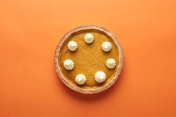 Vista superior de delicioso pastel de calabaza con crema batida en la superficie naranja - foto de stock