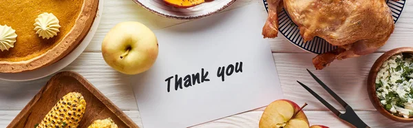 Blick von oben auf gebratenen Truthahn, Kürbiskuchen und gegrilltes Gemüse, serviert in der Nähe von Dankeskarte auf weißem Holztisch — Stockfoto