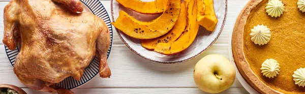 Vue de dessus de dinde rôtie, tarte et citrouille grillée servis sur table en bois blanc — Photo de stock