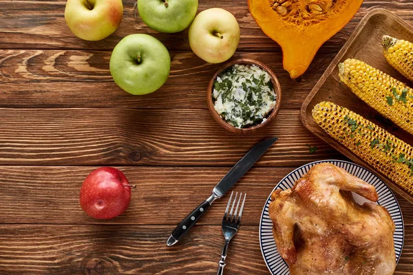 Vue de dessus des pommes, de la dinde rôtie, de la citrouille et du maïs grillé servi sur une table en bois — Photo de stock