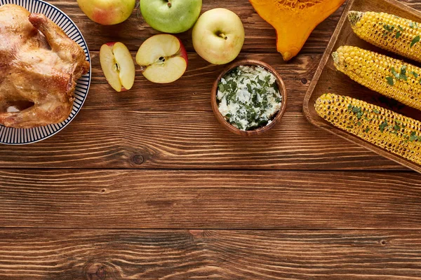 Vista superior de maçãs, peru assado, abóbora e milho grelhado servido em mesa de madeira — Fotografia de Stock