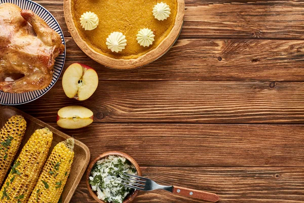 Top view of roasted turkey, pumpkin pie and grilled corn served on wooden table — Stock Photo