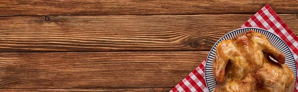 Vista dall'alto di tacchino arrosto su tovagliolo plaid rosso servito su tavolo di legno, colpo panoramico — Foto stock