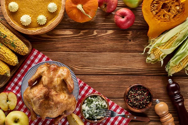 Vista superior de pavo asado, pastel de calabaza y verduras a la parrilla servidas en mesa de madera - foto de stock