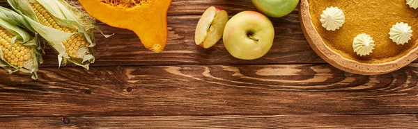 Top view of pumpkin pie and seasonal vegetables served on wooden table, panoramic shot — Stock Photo
