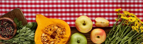 Vista superior de la calabaza, maíz con pimienta, flores amarillas y manzanas en la mesa de madera con servilleta roja, plano panorámico - foto de stock