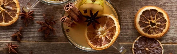 Vue de dessus du vin chaud traditionnel poire en verre avec des épices sur table rustique en bois, vue panoramique — Photo de stock