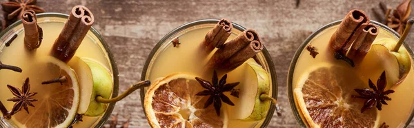 Top view of traditional pear mulled wine in glasses with spices on wooden rustic table, panoramic shot — Stock Photo