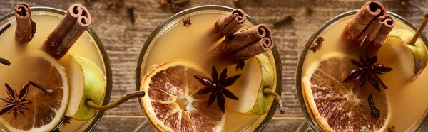 Top view of traditional pear mulled wine in glasses with spices on wooden rustic table, panoramic shot — Stock Photo