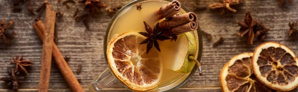 Top view of traditional pear mulled wine in glass with spices on wooden rustic table, panoramic shot — Stock Photo