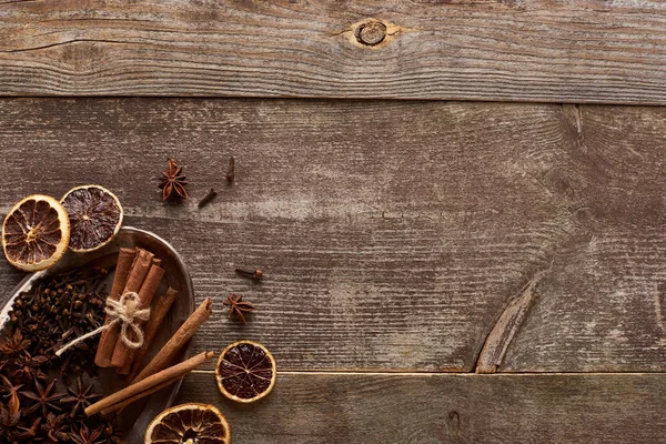 Vue du dessus de bâtonnets de cannelle, d'anis et d'agrumes séchés sur table rustique en bois — Photo de stock