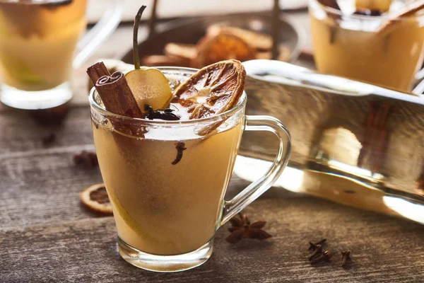 Chaud saisonnier traditionnel poire vin chaud avec des épices en verre sur table rustique en bois — Photo de stock