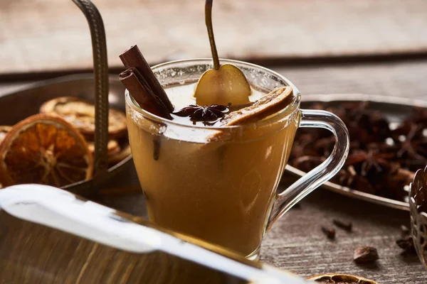 Selective focus of seasonal traditional pear mulled wine with spices in glass on wooden rustic table — Stock Photo