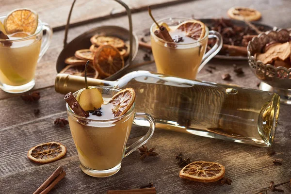 Selective focus of seasonal traditional pear mulled wine with spices in glasses on wooden rustic table — Stock Photo