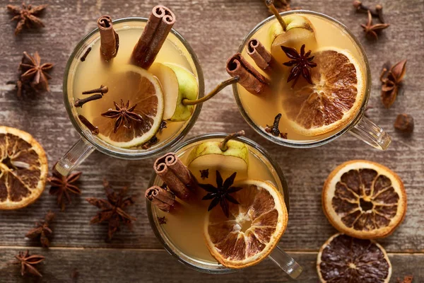 Blick von oben auf saisonale Birnen-Glühweincocktails mit Gewürzen und getrockneten Zitrusfrüchten auf rustikalem Holztisch — Stockfoto