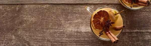 Top view of traditional warm pear mulled wine cocktail with spices and dried citrus on wooden rustic table, panoramic shot — Stock Photo