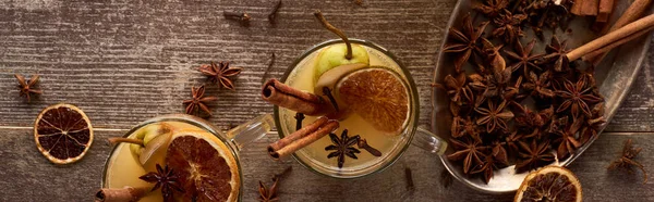 Top view of traditional warm pear mulled wine with spices and dried citrus on wooden rustic table, panoramic shot — Stock Photo